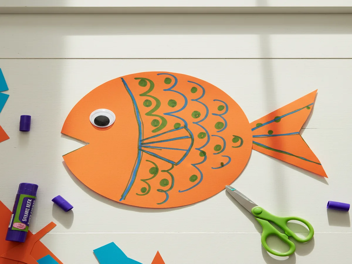 Handmade paper fish craft made from a colored circle with a triangle wedge tail and marker decorations