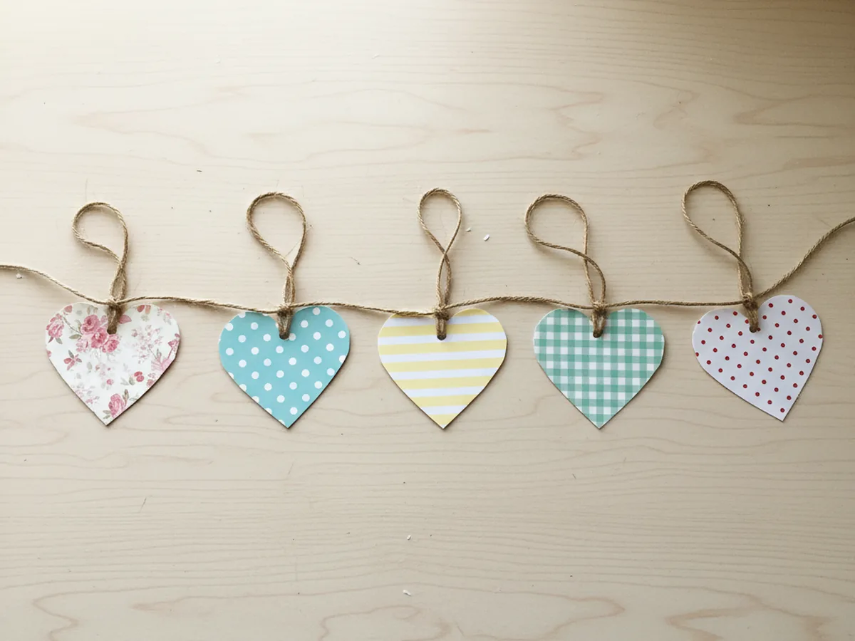 A handmade heart garland made from layered patterned paper hearts in florals, polka dots, and stripes strung on baker's twine