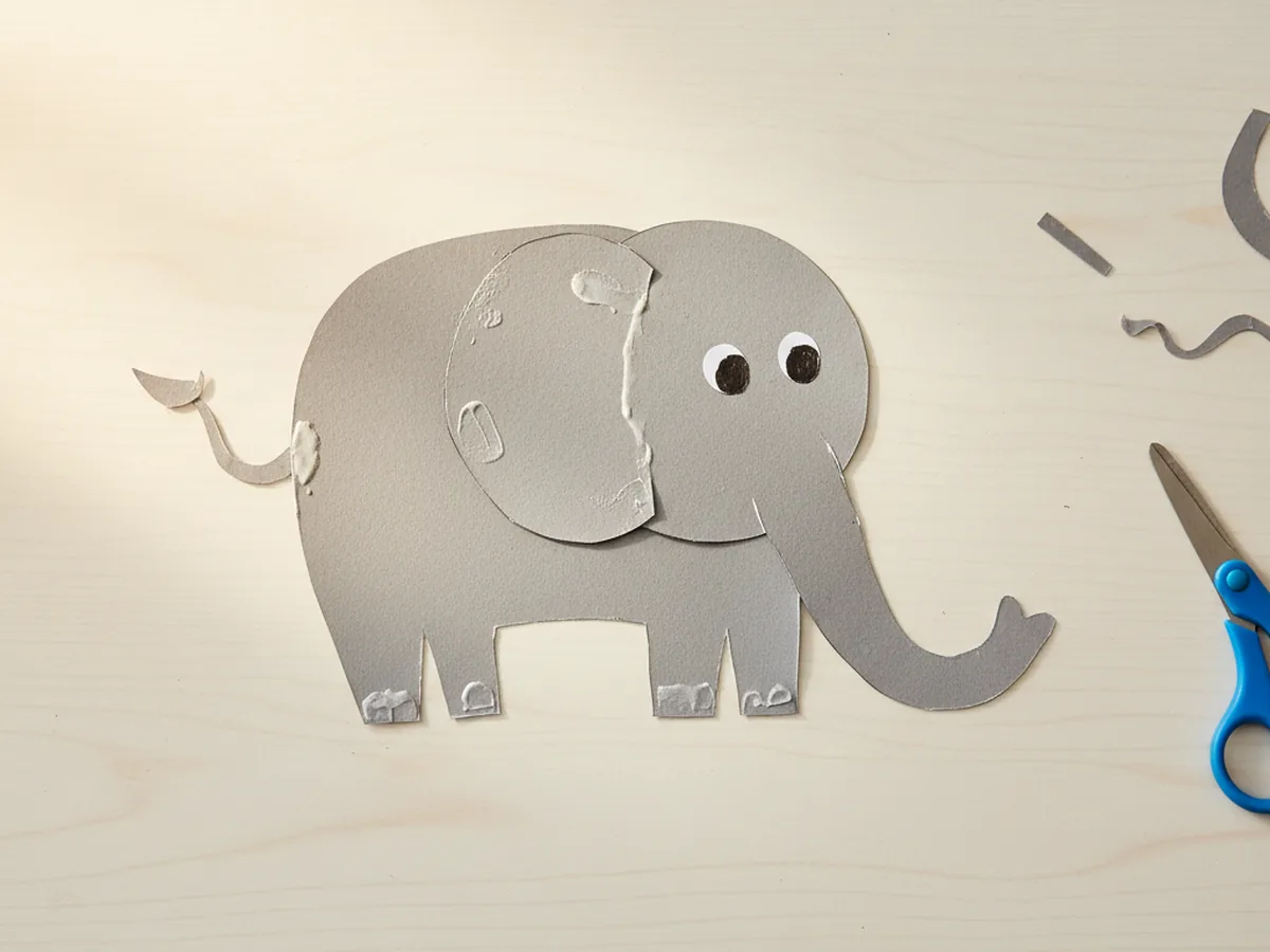 A handmade paper elephant made from grey paper shapes with large round ears, a curled trunk, and gentle drawn eyes