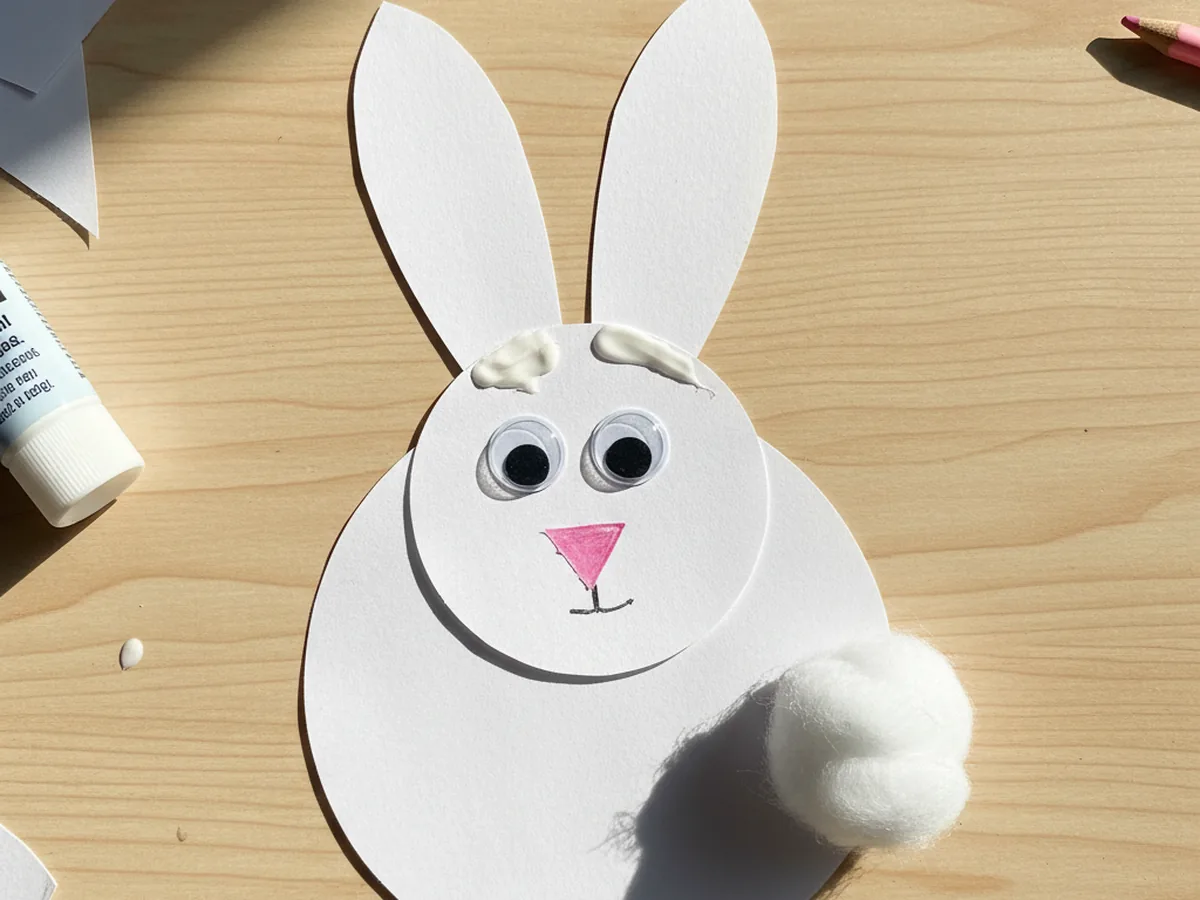 Handmade white paper bunny made from stacked paper circles with pink nose and googly eyes