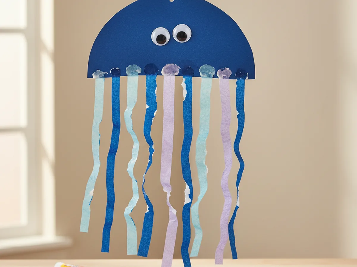 Handmade paper jellyfish with blue paper dome body and flowing tissue paper tentacles