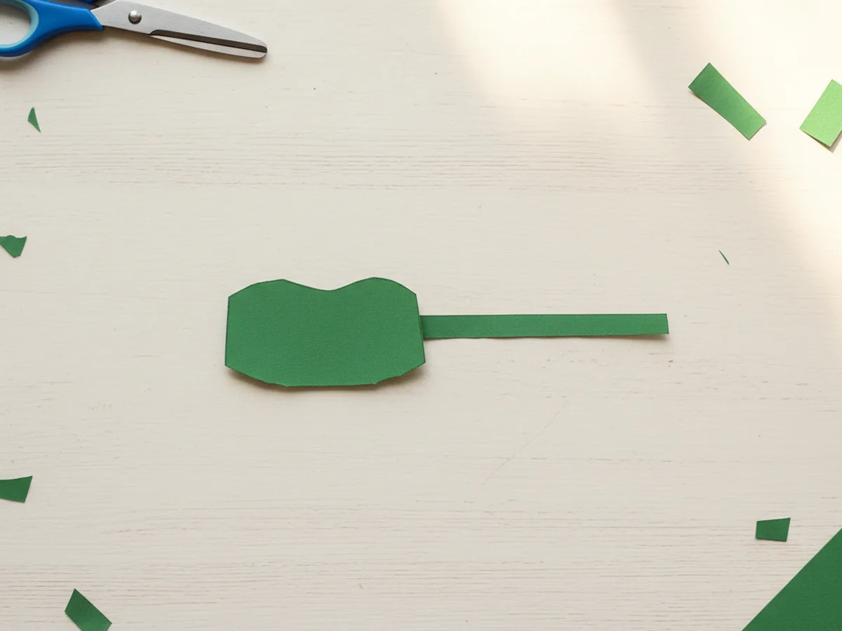A small green paper turret rectangle with a rounded top next to a long thin green paper strip for the barrel of a paper craft tank