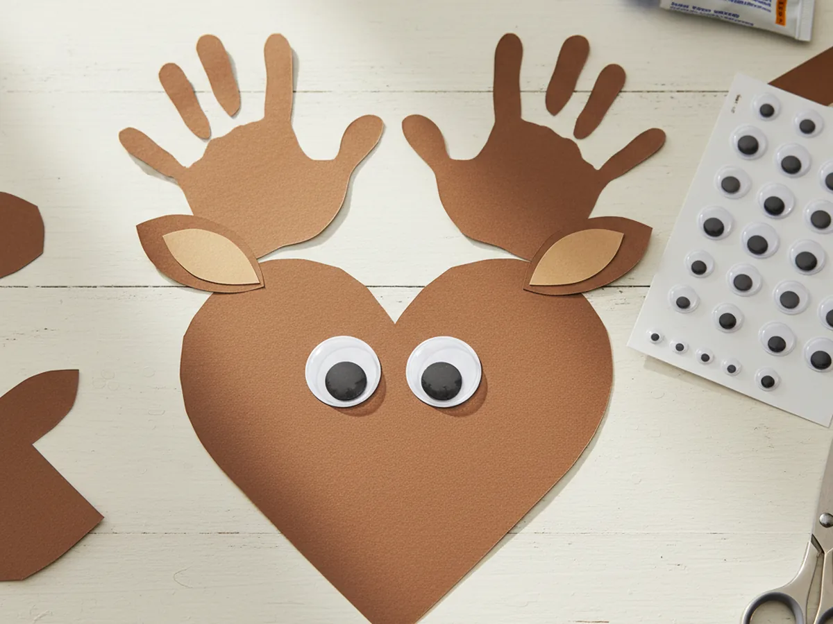 Two large googly eyes added to the upper middle of the brown reindeer face just below the antlers, instantly giving the paper reindeer craft a sweet personality