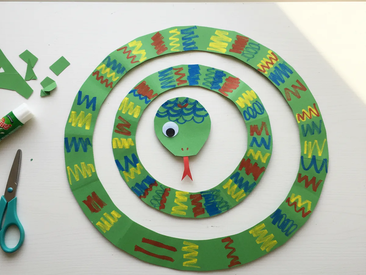 Finished colorful paper snake craft made from a green construction paper spiral on a white craft table