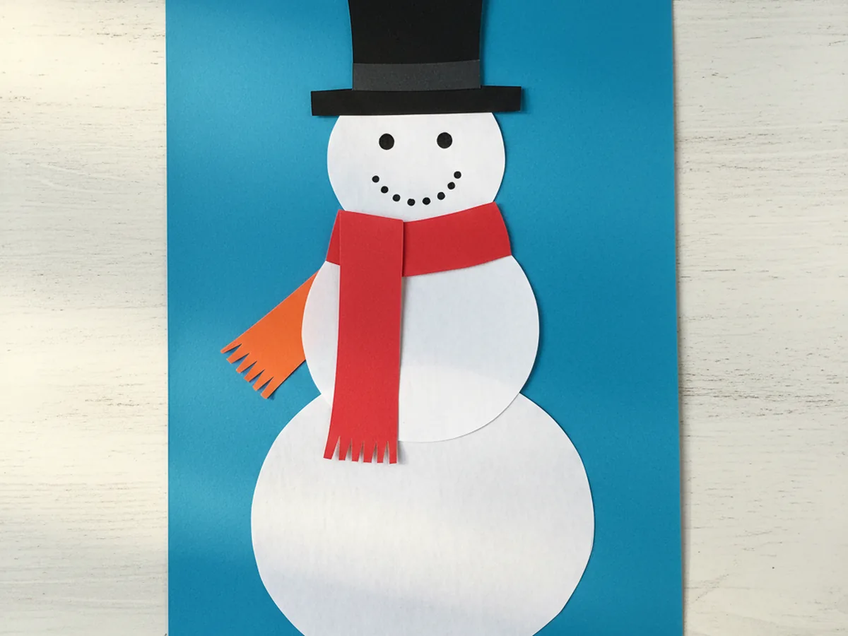 Snowman paper craft with a colorful red and orange paper scarf wrapped around the neck area between head and body circles