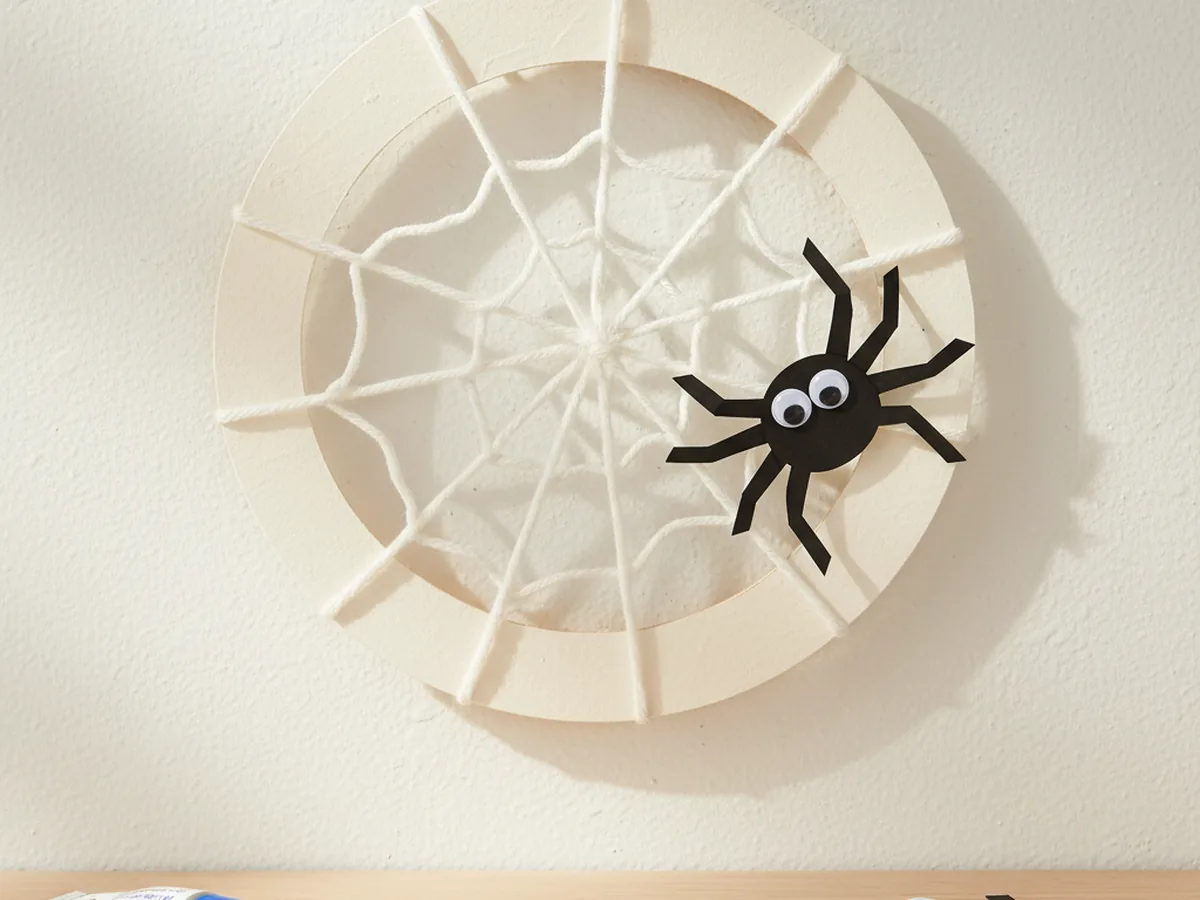 Handmade paper spider web wreath with white yarn web and a small paper spider on the side